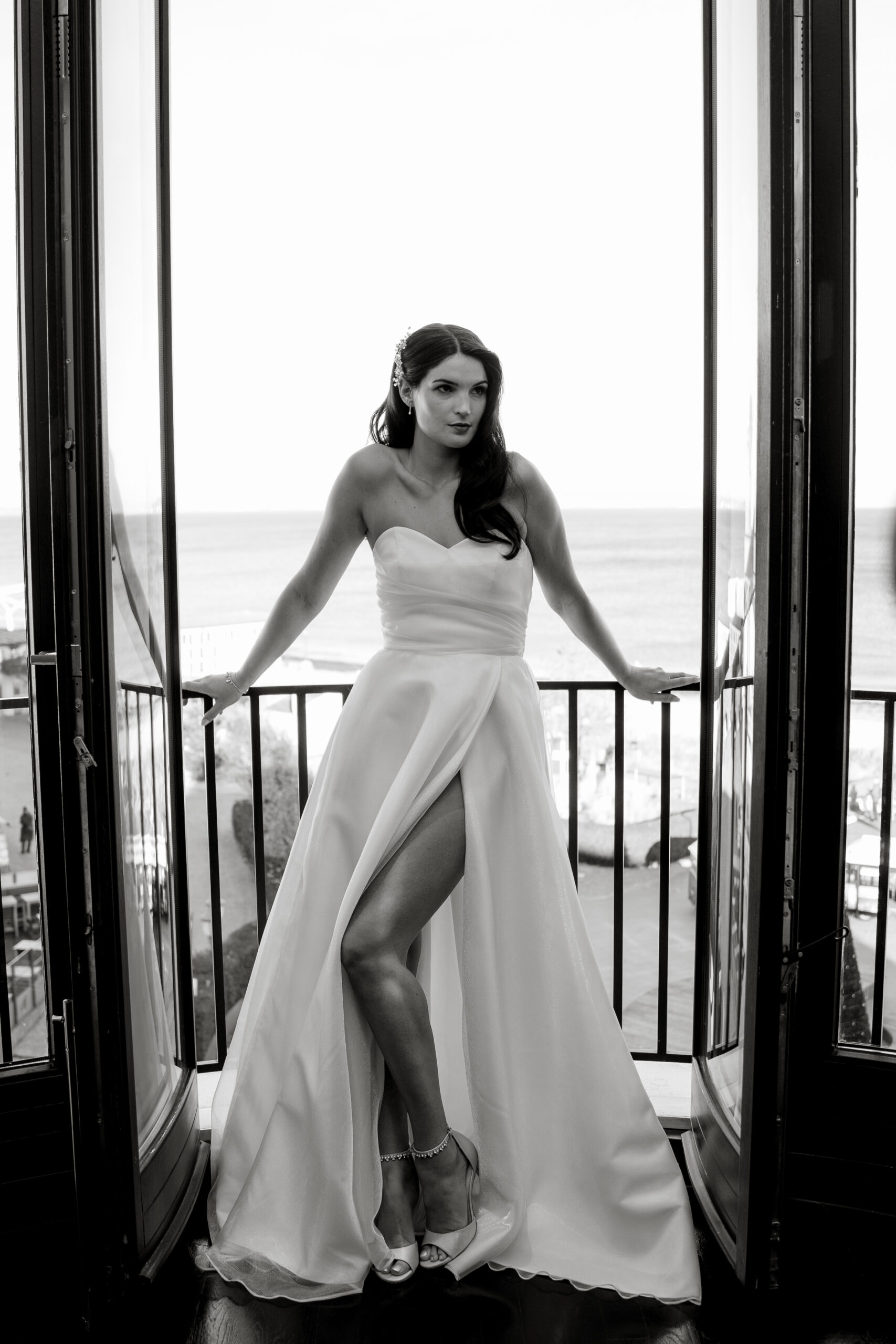 Eine Frau im trägerlosen Kleid posiert in einem Hauseingang mit Blick auf die Ostsee im Hintergrund - die perfekte Inspiration für alle Hochzeitsplaner, die von einer Hochzeit auf Rügen träumen.