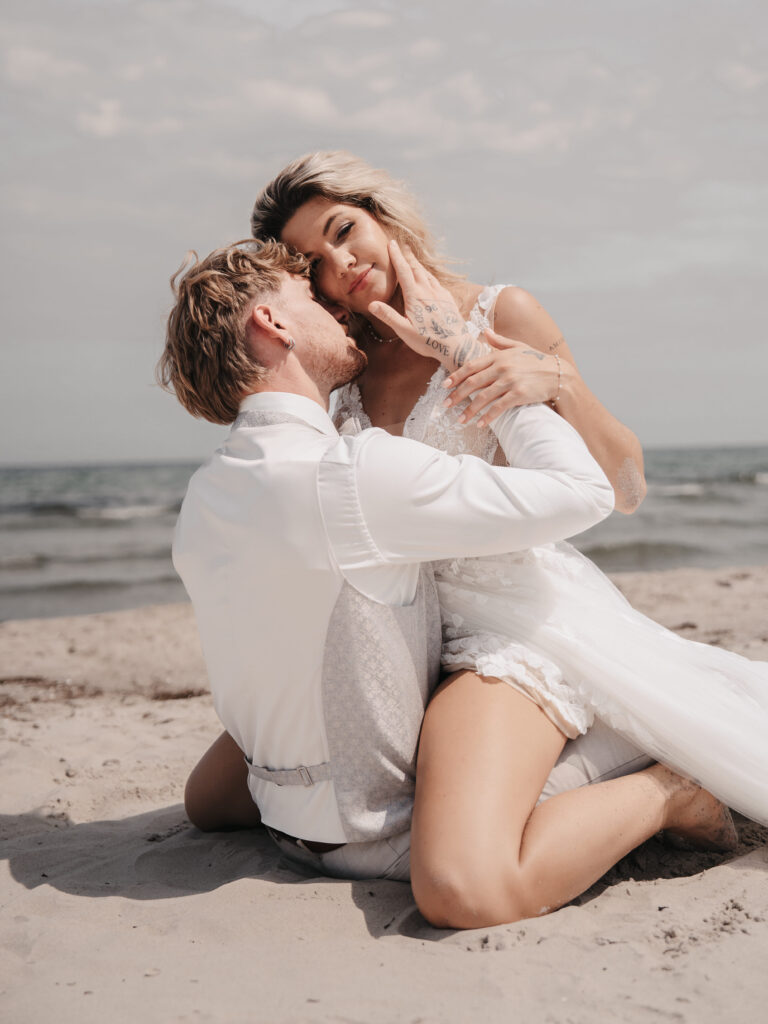 Ein Mann und eine Frau sitzen am Strand und träumen von ihrer Strandhochzeit und dem unvergesslichen Gefühl, am Meer zu heiraten.