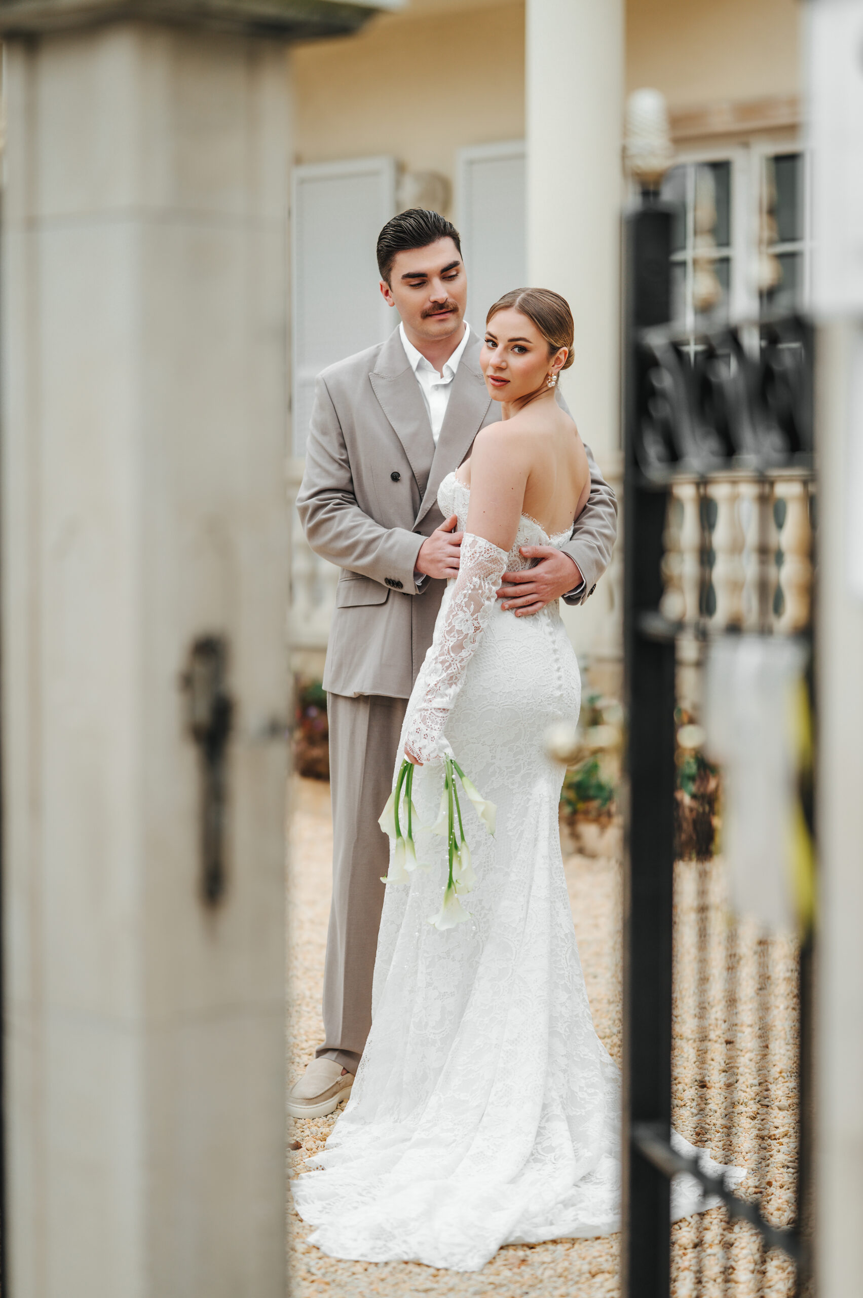 Braut in weißem Kleid und Bräutigam in beigem Anzug posieren gemeinsam im Freien auf Sylt, die Braut hält weiße Blumen, perfekt eingefangen von einem Hochzeitsplaner.