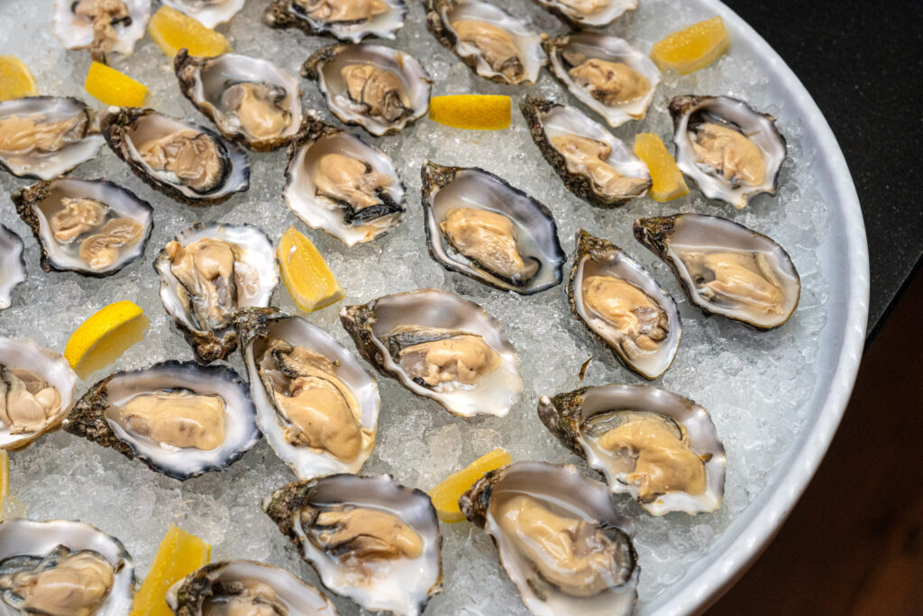 Eine Platte mit rohen Austern auf Eis, garniert mit Zitronenspalten.